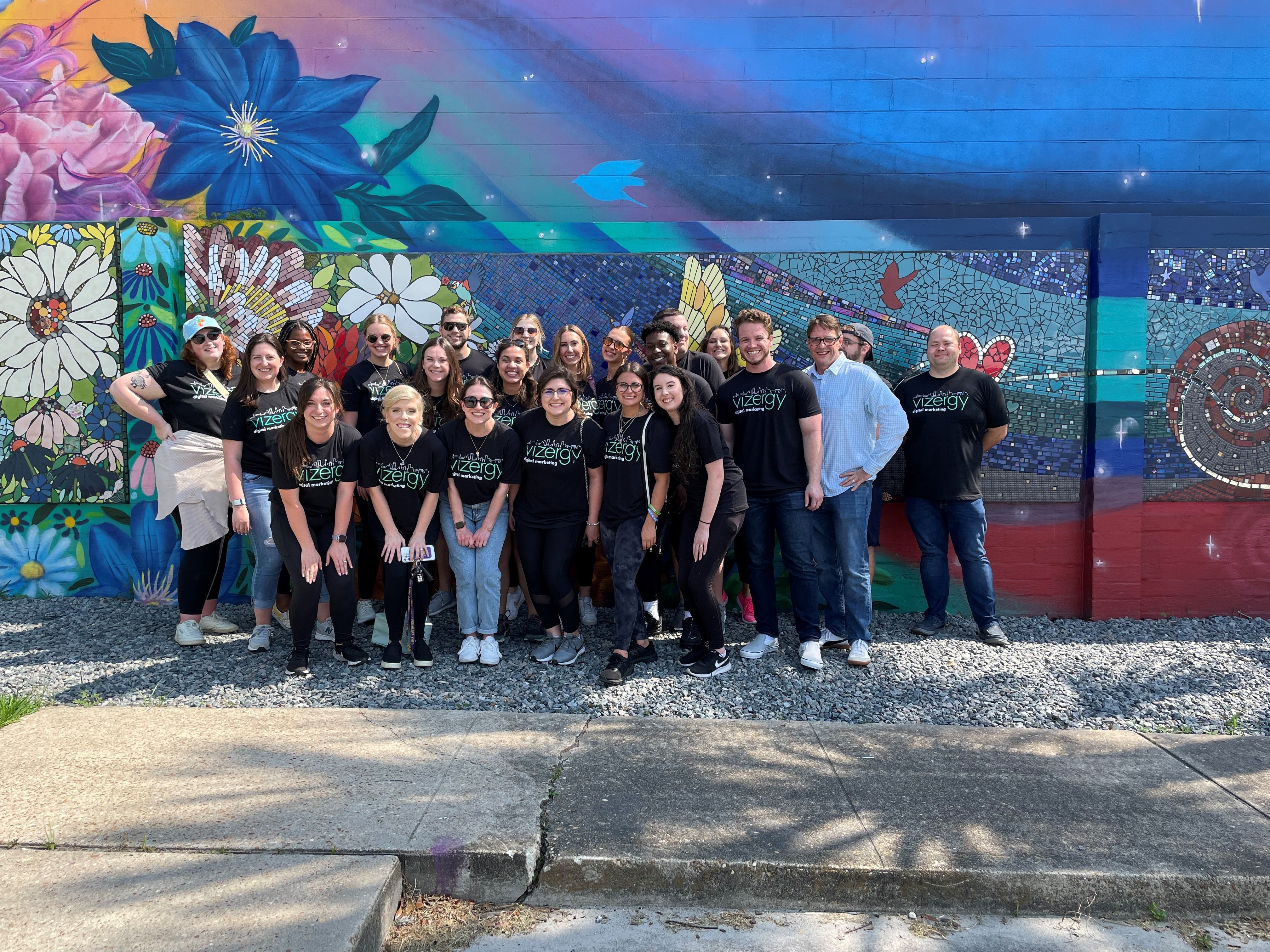 Vizergy employees in front of colorful mural 