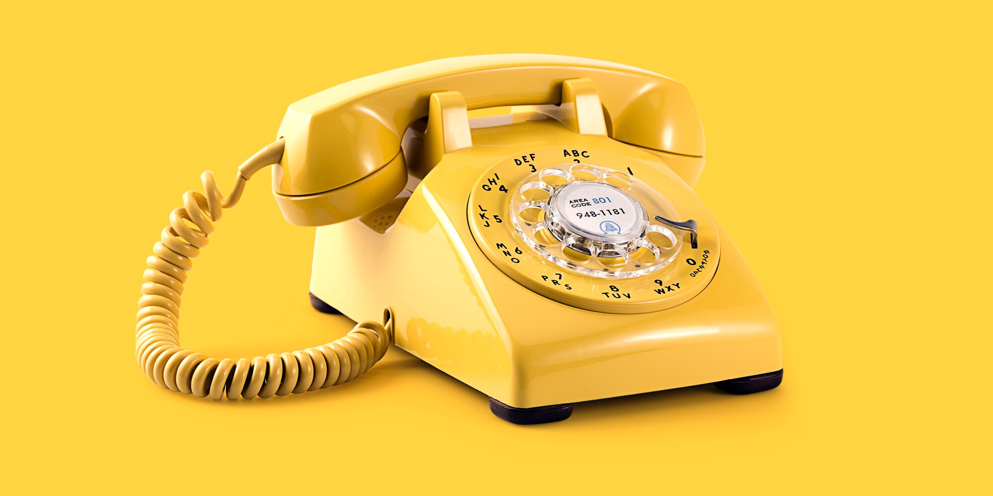 yellow rotary phone on yellow background