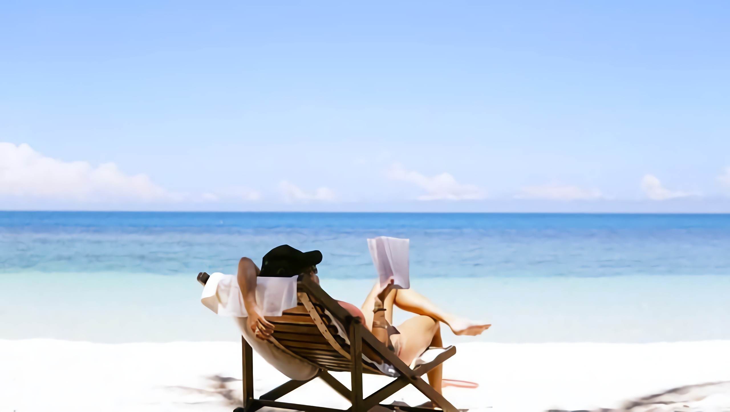 woman reading on the beach in a chair