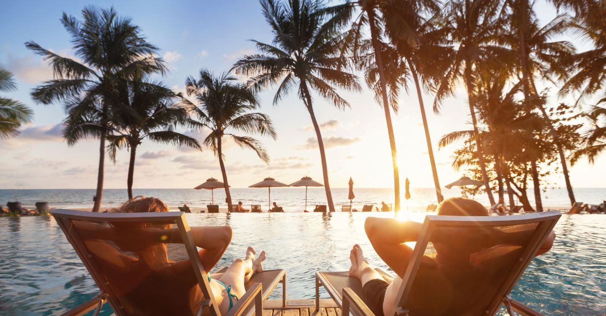 people sitting in chairs by a pool with palm trees