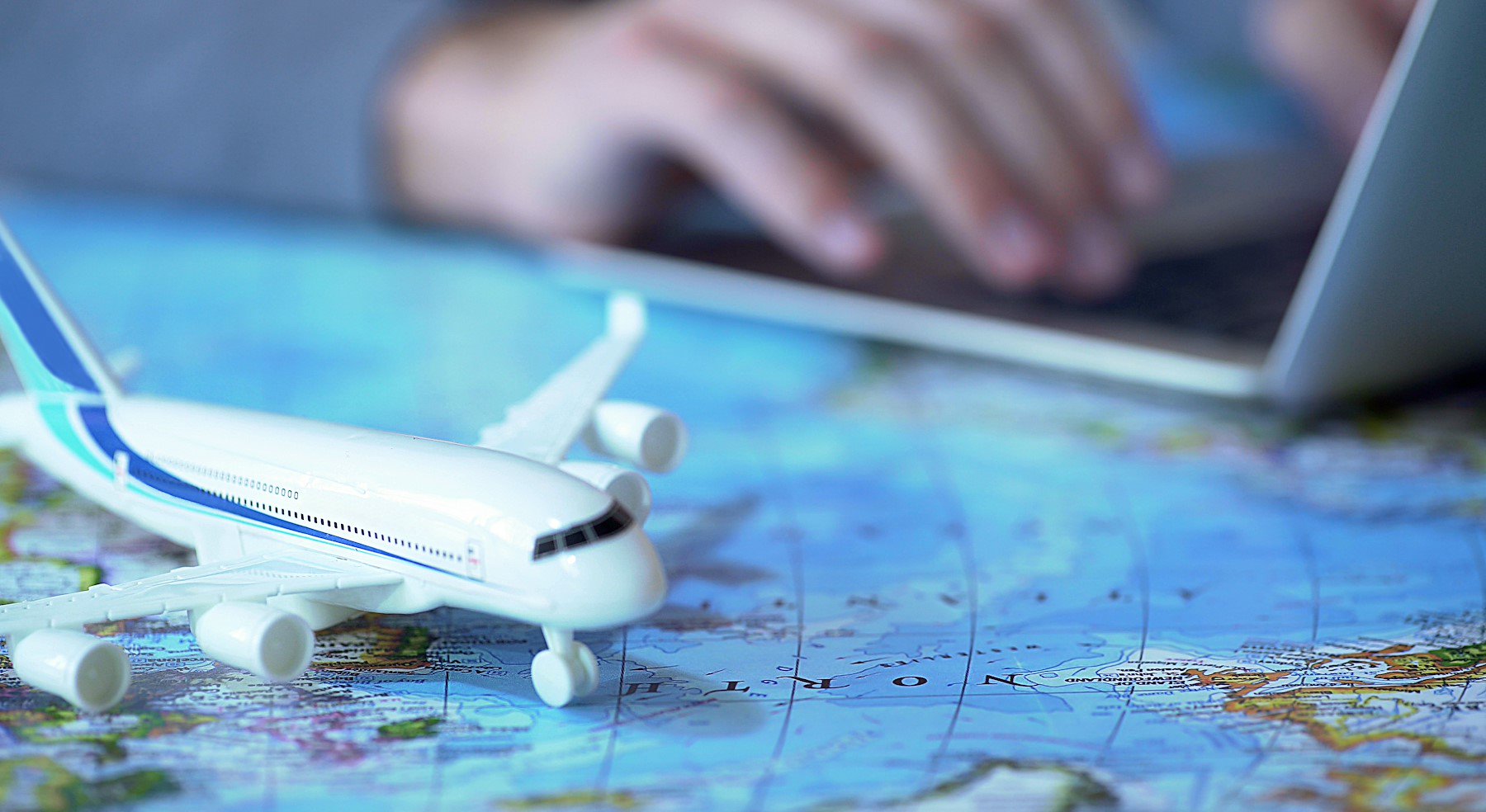 Airplane model closeup, defocused person booking flight tickets