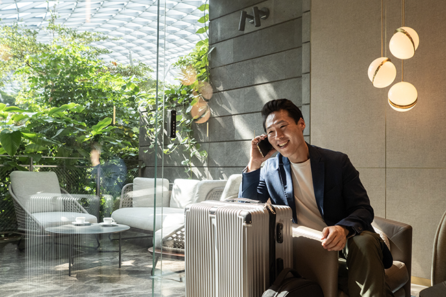 a man sitting on a chair with luggage and a phone